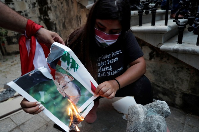 8일(현지시간) 레바논 수도 베이루트 외교부 건물 앞에서 열린 반 정부 시위에서 한 여성이 미셸 아운 대통령 사진을 불태우고 있다. AP/뉴시스