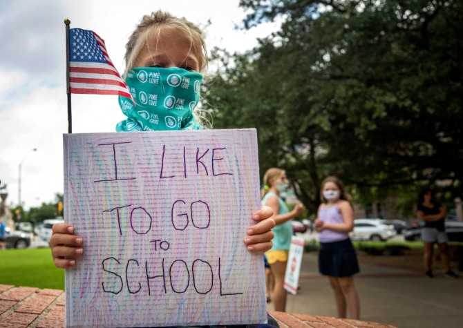 신종 코로나바이러스 감염증(코로나19)이 확산하는 가운데 미국 텍사스주 포트워스에서 7세 아이가 학교에 가고 싶다고 써진 손팻말을 들고 있다. 사진=뉴시스