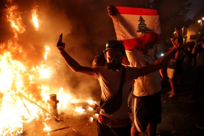 베이루트 폭발 참사 이후 반정부 시위가 이어지는 가운데 11일(현지시간) 시위대가 레바논 국기를 들고 V를 그려 보이고 있다. AP/뉴시스