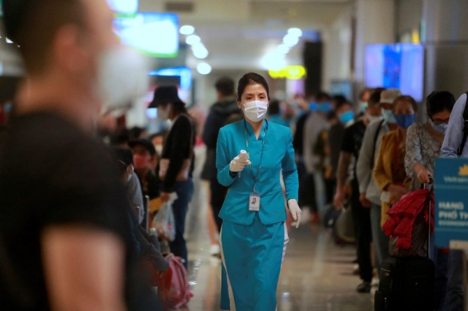 베트남 하노이 공항에서 한 항공사 직원이 탑승객의 체온을 확인하기 위해 온도계를 들고 있다. AP/뉴시스