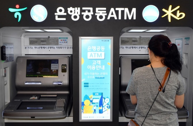 한 고객이 광주 광산구 우산동 이마트광산점에 설치된 신한·KB국민·하나·우리은행 공동 자동화기기(ATM)를 이용하고 있다. 사진=뉴시스