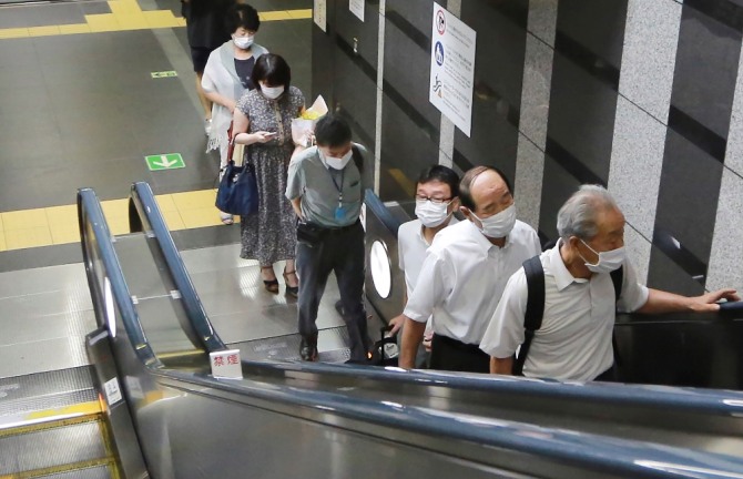 일본 도쿄의 지하철역에서 코로나19 감염을 예방하기 위해 마스크를 쓴 시민들이 에스컬레이터를 타고 있다. AP/뉴시스