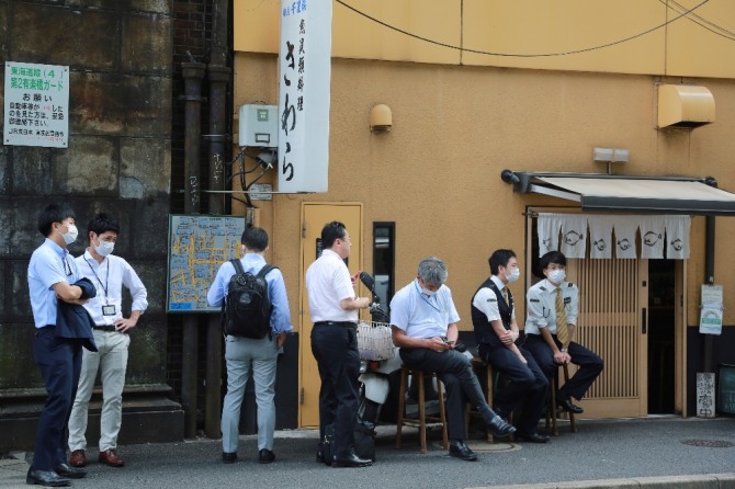 15일 점심시간에 일본 도쿄의 일식집 앞에서 시민들이 마스크를 착용한 채 차례를 기다리고 있다. AP/뉴시스