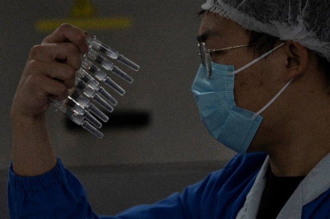 24일 중국 제약회사 시노백(Sinovac) 본사에서 한 직원이 코로나19 백신을 살펴보고 있다. AP/뉴시스