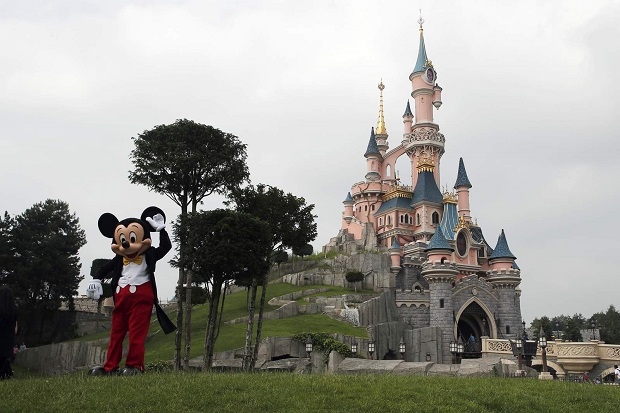 디즈니랜드 파리의 잠자는 숲속의 공주 성앞에서 미키마우스 복장을 입은 디즈니랜드 직원이 포즈를 취하고 있는 모습. 사진=AP/뉴시스