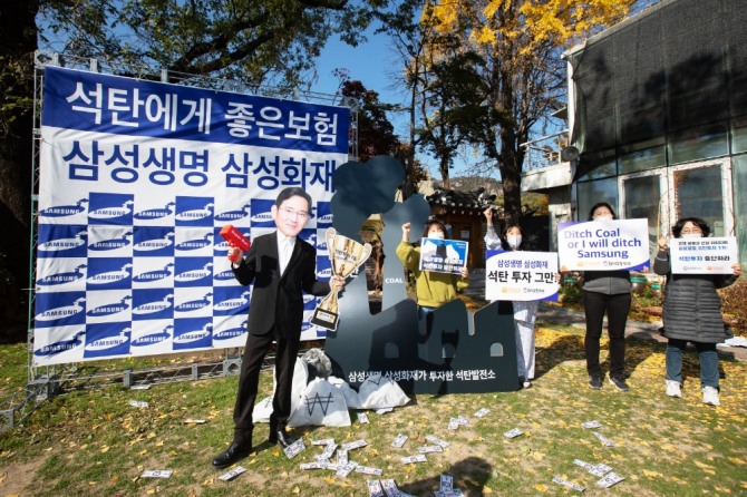 환경운동연합 소속 활동가들이 10일 서울 종로구 환경운동연합 회화나무 마당에서 삼성생명과 삼성화재에 석탄금융 중단을 촉구하는 퍼포먼스를 하고 있다. 사진=기후미디어허브/환경운동연합 제공