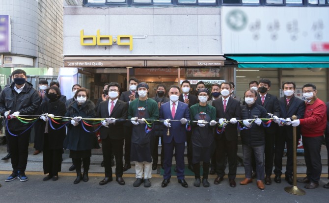 BSK 100호점(강서화곡점)에서 윤홍근 제너시스 BBQ 회장(왼쪽 여섯번째)과 임직원이 기념 촬영을 하고 있다. 사진=제너시스 BBQ
