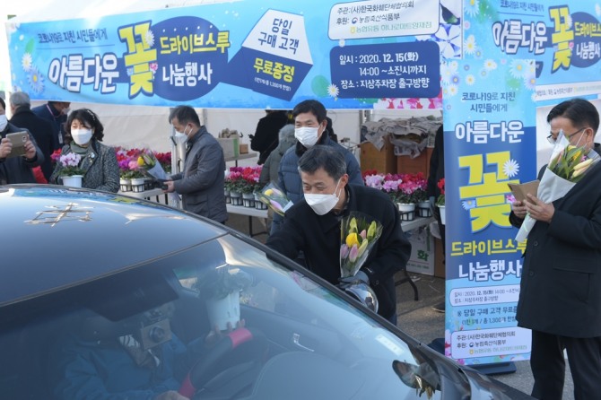 15일 오후 하나로마트 양재점에서 정연태 농협유통 대표가 시민들에게 드라이브 스루 방식으로 꽃을 나눠주고 있다. 사진=농협유통