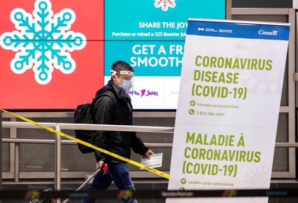 캐나다 토론토공항에서 마스크를 한 채 캐리어를 끌고가는 한 여행객 모습, 사진=로이터