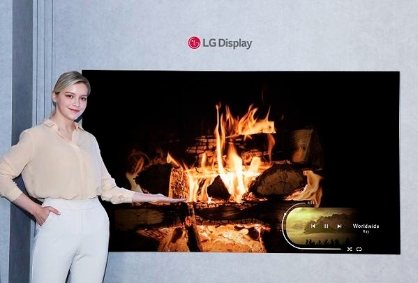 LG디스플레이 모델이 신규 OLED 소자가 적용된 77인치 차세대 OLED TV 패널을 소개하고 있다. 사진=LG디스플레이