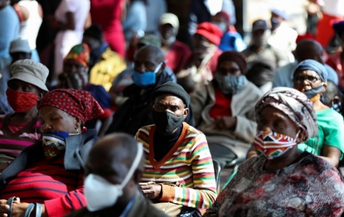 남아프리카 공화국 소웨토 지역 주민들이 신종 코로나 바이러스 감염증 확산을 막기 위한 정부 보조금을 받기 위해 기다리며 앉아 있다. 사진=로이터