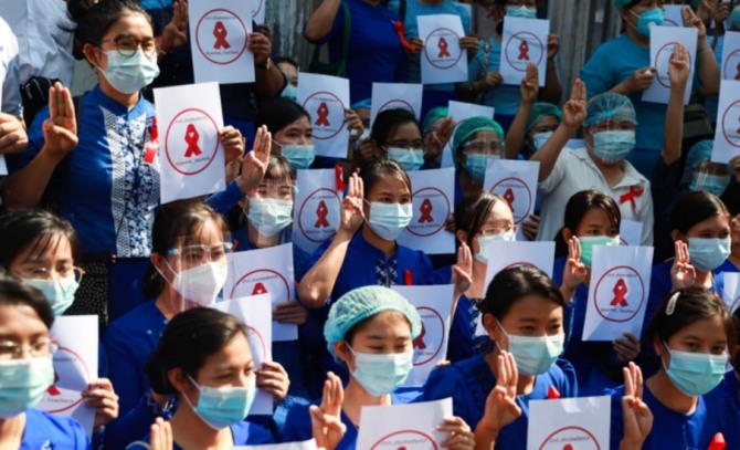 5일 미얀마 양곤의 양곤 교육대 캠퍼스 앞에 교사들이 모여 미얀마 교사들, 시민 불복종이라고 쓰인 팻말을 들고 세 손가락을 들어 군부 쿠데타에 저항하는 표시를 하고 있다. 사진=AP/뉴시스 