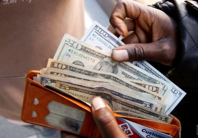 한 남성이 은행에서 현금을 인출한 뒤 달러화 지폐를 정리하고 있다. 사진=로이터