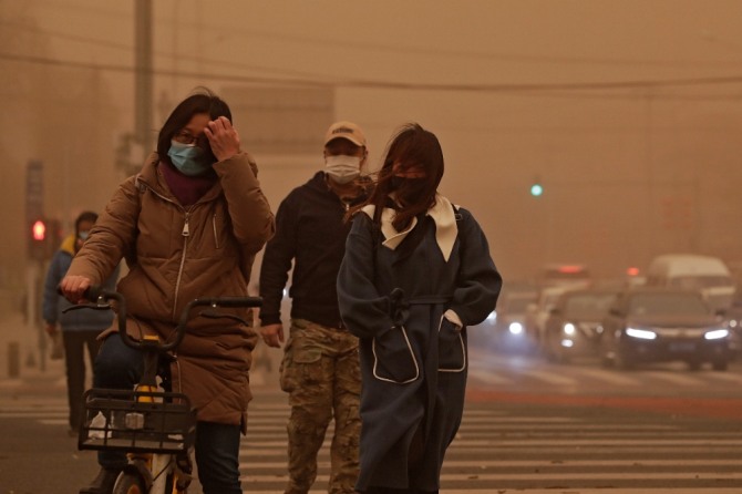 중국 베이징에서 마스크를 쓴 시민들이 공기 오염과 황사로 뿌연 거리를 지나고 있다. AP=뉴시스