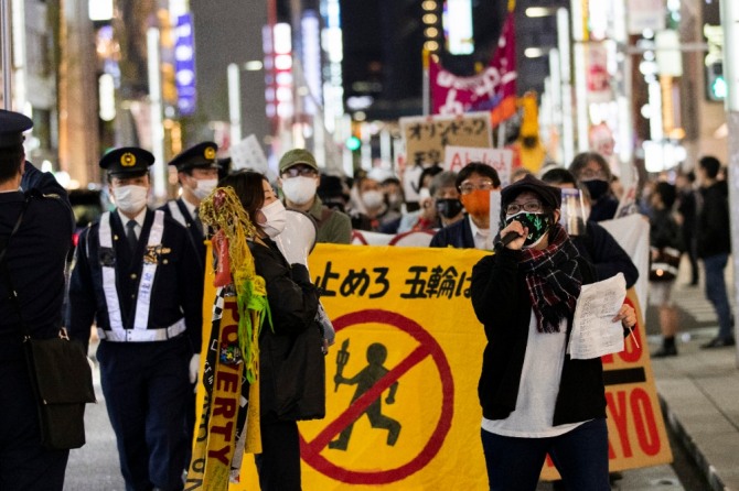 지난달 25일 일본 도쿄에서 2020 도쿄올림픽·패럴림픽 강행에 반대하는 시위대가 성화봉송 반대 현수막을 들고 긴자 거리를 행진하고 있다. 사진=뉴시스