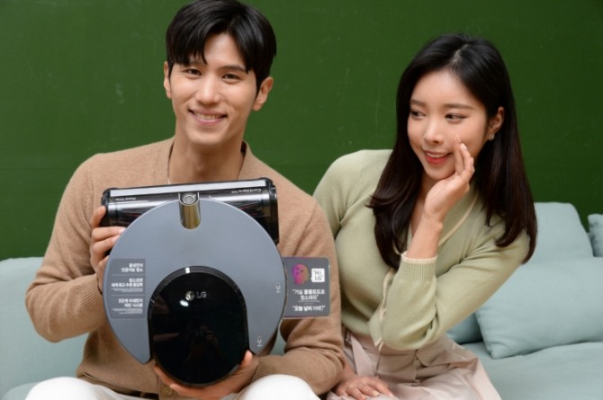  LG전자 모델들이 똑똑해진 로봇청소기 ‘LG 코드제로 씽큐 R9 보이스’를 소개하고 있다. 사진=LG전자