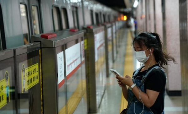 마스크를 쓴 중국 여성이 중국 베이징 지하철 역에서 스마트폰을 보고 있는 모습. 사진=로이터 
