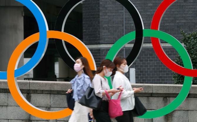 일본 도쿄에서 코로나19 확산 방지를 위해 마스크를 쓴 사람들이 도쿄 올림픽 오륜 조형물 앞을 지나가고 있다. 사진=뉴시스