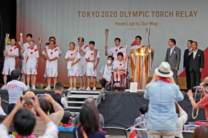 지난 6월 29일 가나가와현 사가미하라에서 예정한 도쿄올림픽 가두 성화봉송이 수도권 방역을 이유로 취소되자 성화 주자들이 실외에서 대체해 열린 이벤트에 참석해 기념촬영을 하고 있다. 