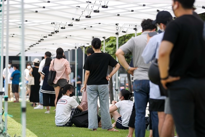 서울 용산구 용산역 광장에 설치된 신종 코로나바이러스 감염증(코로나19) 임시선별검사소를 찾은 시민들이 23일 오전 폭염에 지쳐 잠시 잔디에 앉아 쉬고 있다. 사진=뉴시스