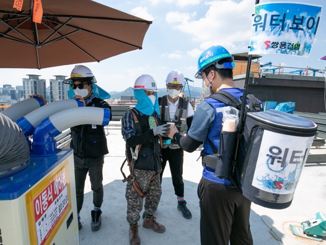 쌍용건설 현장 보건관리자가 얼음물 탱크를 등에 맨 ‘워터보이’로 변신해 건설현장 곳곳을 다니며 쿨스카프를 착용한 근로자들에게 시원한 물을 전해주고 있다. 사진=쌍용건설