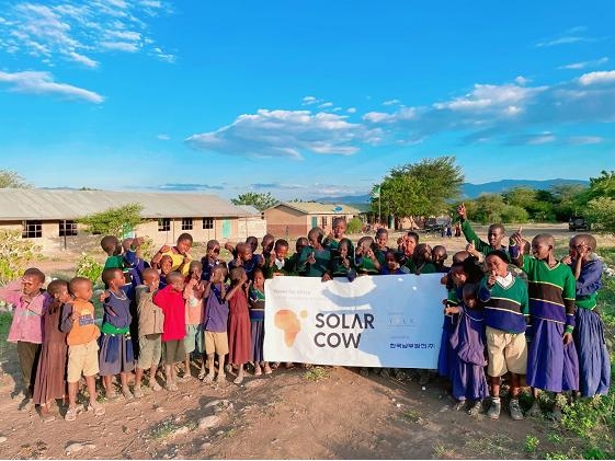 탄자니아 음바쉬 초등학교 학생들이 태양광 배터리 충전시설 솔라카우 설치를 기념해 기념사진을 찍고 있다. 사진=한국남부발전 