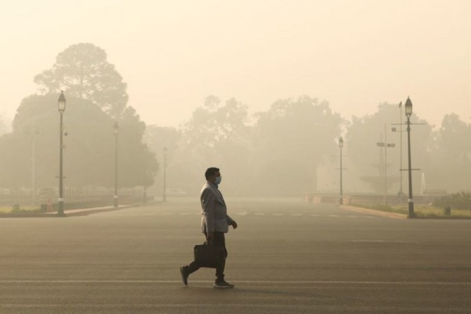 지난해 12월 23일(현지시간) 한 직장인이 짙은 먼지로 가시거리가 짧은 인도 수도 뉴델리의 거리를 거닐고 있다. 사진=로이터