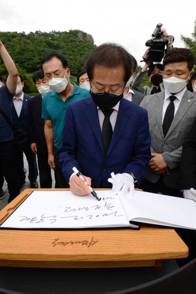 국민의 힘 대권 주자인 홍준표 의원이 지난 3일 오후 경남 김해시 봉하마을을 찾아 고(故) 노무현 전 대통령 묘소에 참배하고 방명록을 쓰고 있다. 사진=뉴시스