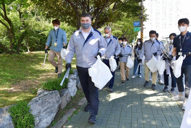 카허 카젬(앞줄 가운데 한국지엠 사장 등 한국지엠 임직원들이 14일 인천 부평 본사에서 쓰레기를 줍고 있다. 사진=한국지엠 