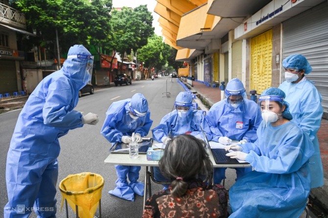 의료진이 하노이 동다(Dong Da) 지역에서 코로나19 백신을 접종하기 전에 사람들을 검사하기 위해 샘플을 채취하고 있다. 