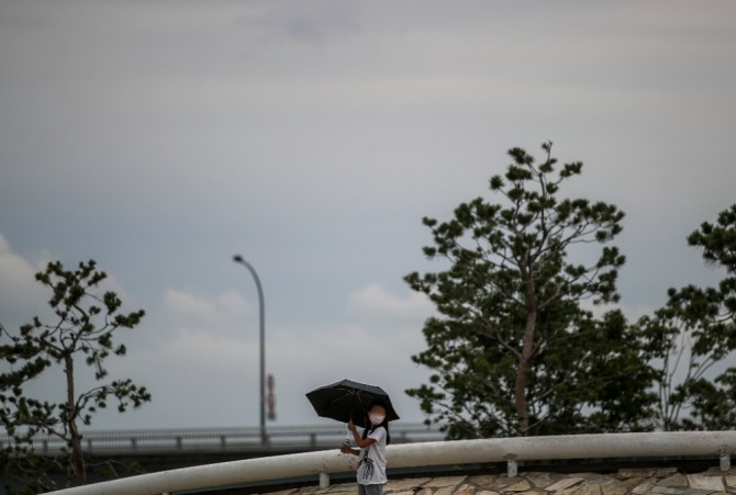 이달 27일 오후 서울 서초구 반포한강시민공원에서 갑자기 내린 비에 우산을 쓴 시민이 발걸음을 옮기고 있다. 사진=뉴시스