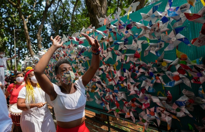 6일(현지시간) 브라질 상파울루에서 코로나19로 숨진 희생자 추모 행사가 열려 참가자들이 희생자들을 상징하는 바람개비로 장식된 골목에서 추모 춤을 추고 있다. 사진=뉴시스