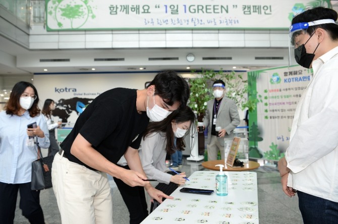 코트라(KOTRA) 직원들이 지난 15일 '1일 1그린' 친환경 실천을 서약하고 약속나무에 서약카드를 걸고 있다. 사진=코트라