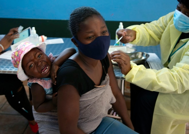 아이를 업은 남아프리카공화국(남아공) 여성이 26일 요하네스버그 검역소에서 화이자 백신을 접종하고 있다. 새 코로나 변이 ’오미크론‘이 남아공에서 급속도로 확산하자 세계 각국이 연일 빗장을 걸어 잠그고 있다. 사진=뉴시스