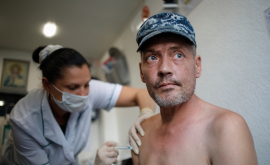 11일(현지시간) 러시아 상트페테르부르크의 한 이동식 코로나19 백신 접종소에서 의료 관계자가 한 노숙인에게 스푸트니크 라이트 백신을 접종하고 있다. 사진=뉴시스