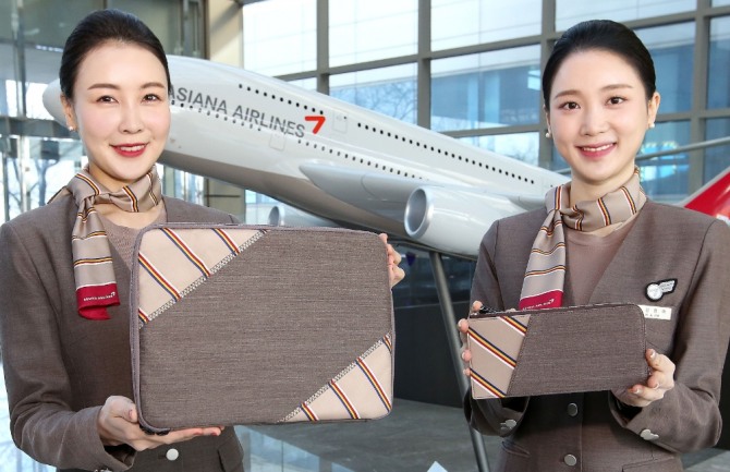 아시아나항공 승무원들이 회수한 유니폼을 이용해 제작한 업사이클링 제품인 태블릿파우치를 선보이고 있다. 사진=아시아나항공
