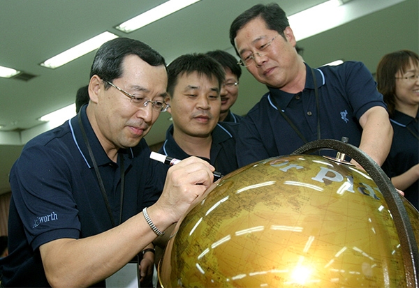 2005년 LS혁신 한마당에 참석한 구자홍 회장이 직원들이 보는 가운데 지구본에 메시지를 남기고 있다. 사진=LS그룹