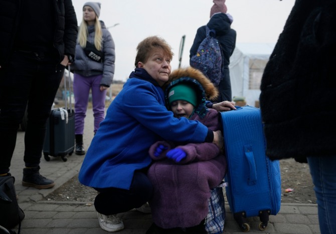 3일(현지시간) 폴란드 동부 국경도시 메디카에 도착한 우크라이나 난민 여성이 가방에 앉아 우는 소녀를 안아서 달래주고 있다. 사진=뉴시스