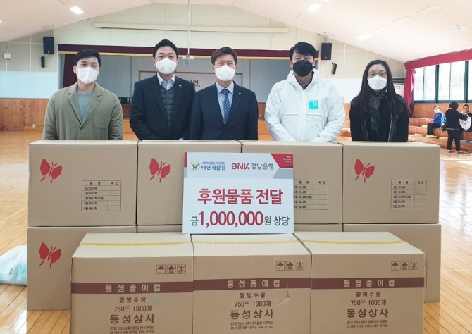 BNK경남은행 김후동 지점장(가운데)이 (사)태연학원 강병준 사무국장에게 코로나19 극복 후원물품을 전달하고 있다.  [사진=BNK경남은행]