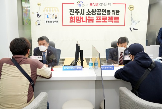 BNK경남은행 최홍영 은행장(뒷줄 왼쪽 첫번째)과 진주시 조규일 시장(뒷줄 왼쪽 두번째)이 지역 소상공인들에게 금융상담을 하고 있다.  [사진=BNK경남은행]