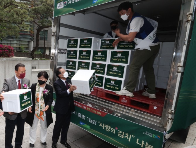 (왼쪽부터)국민의힘 홍문표 의원, 더불어민주당 서영교 의원, 이성희 농협중앙회장이 한국농협김치 출범기념 사랑의 김치나눔 행사에서 소외계층에게 전달할 김치를 옮기고 있다. [사진=농협]