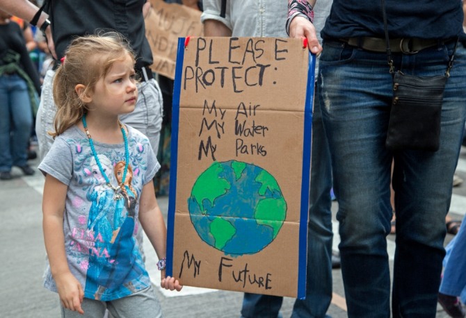 기후변화에 대한 경각심을 일깨우기 위해 어린 소녀가 부모와 함께 공기, 물, 공원을 보호하자는 피켓을 들고 시위하고 있다. 자료=글로벌이코노믹