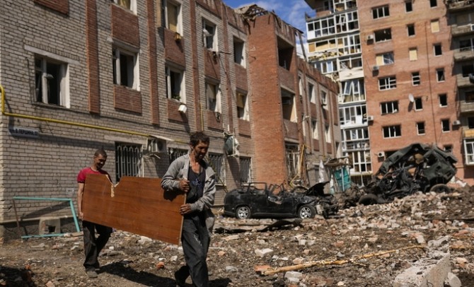 지난달 24일(현지시간) 우크라이나 동부 바흐무트의 파괴된 건물 주변에서 주민들이 널빤지를 옮기고 있다. [사진=뉴시스]