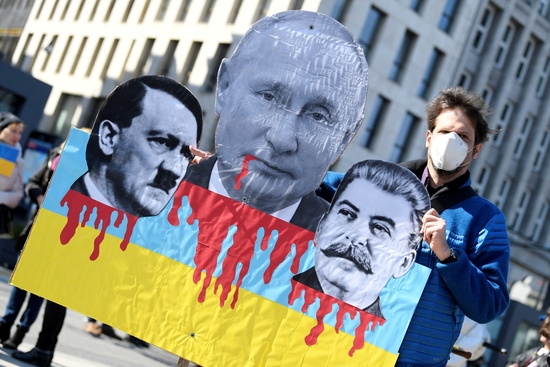 한 반전 시위자가 블라디미르 푸틴 러시아 대통령과 아돌프 히틀러, 이오시프 스탈린의 사진이 담긴 펼침막을 들고 있다. 사진=로이터