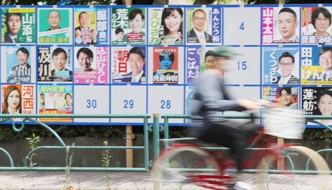 일본 참의원 선거 투표일인 10일 오후 도쿄도 스미다구에 설치된 후보자 안내판 앞으로 자전거를 탄 사람이 지나가고 있다.사진=연합뉴스