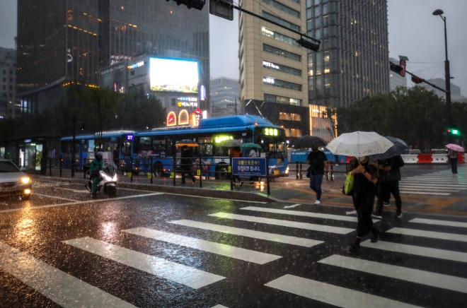 전국적으로 장맛비가 내리고 있는 23일 오후 서울 종로구 광화문광장 인근에서 쏟아지는 폭우에 시민들이 우산을 쓴 채 이동하고 있다. 사진=뉴시스