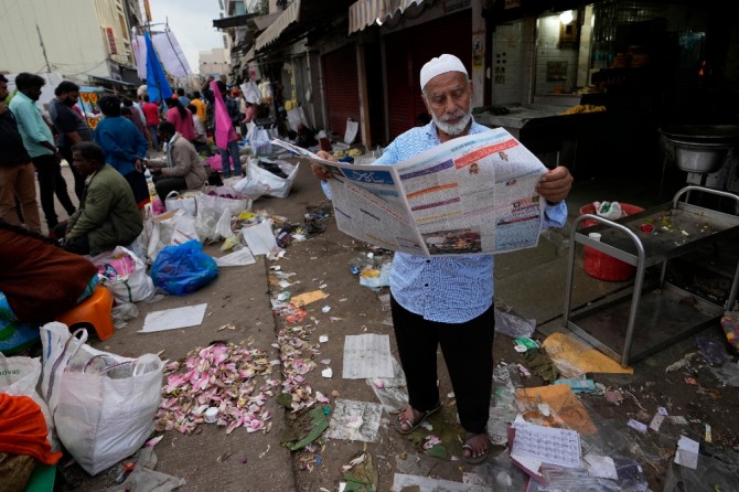 지난 4월 13일(현지시간) 인도 벵갈루루의 도매시장에서 마스크를 쓰지 않은 한 남성이 신문을 읽고 있는 모습.사진=뉴시스