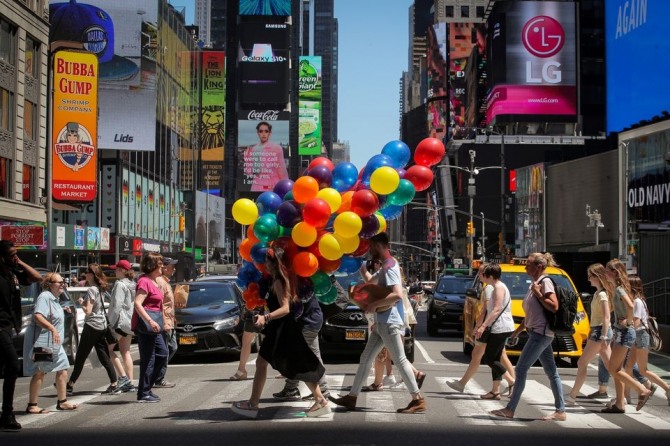 한꾸러미의 풍선을 들고 한 여성이 뉴욕 타임스퀘어 거리를 걷고 있다. 사진=로이터