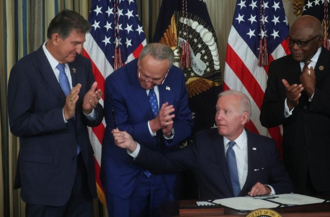조 바이든 미국 대통령이 16일(현지시간) 백악관에서 '인플레이션 감축법안'에 서명한 뒤 이때 사용한 펜을 조 맨친 상원의원에게 주고 있다. 사진=로이터
