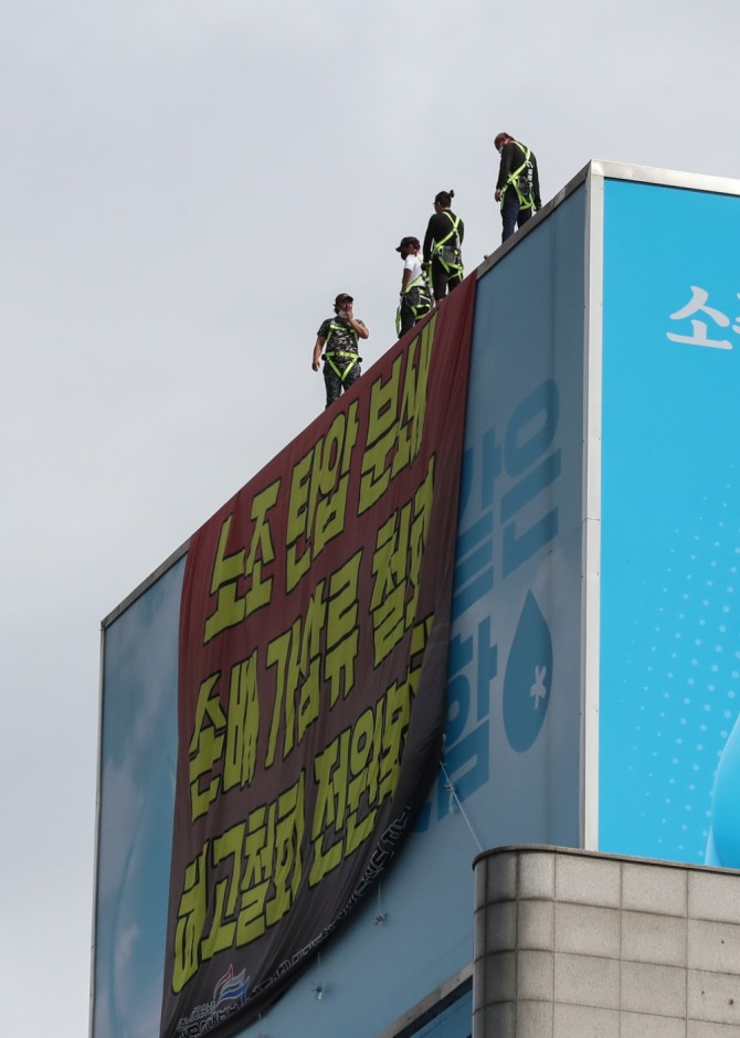 24일 오전 서울 강남구 하이트진로 본사 옥상에서 민주노총 공공운수노조 화물연대 조합원이 내려다보고 있다. 사진=뉴시스